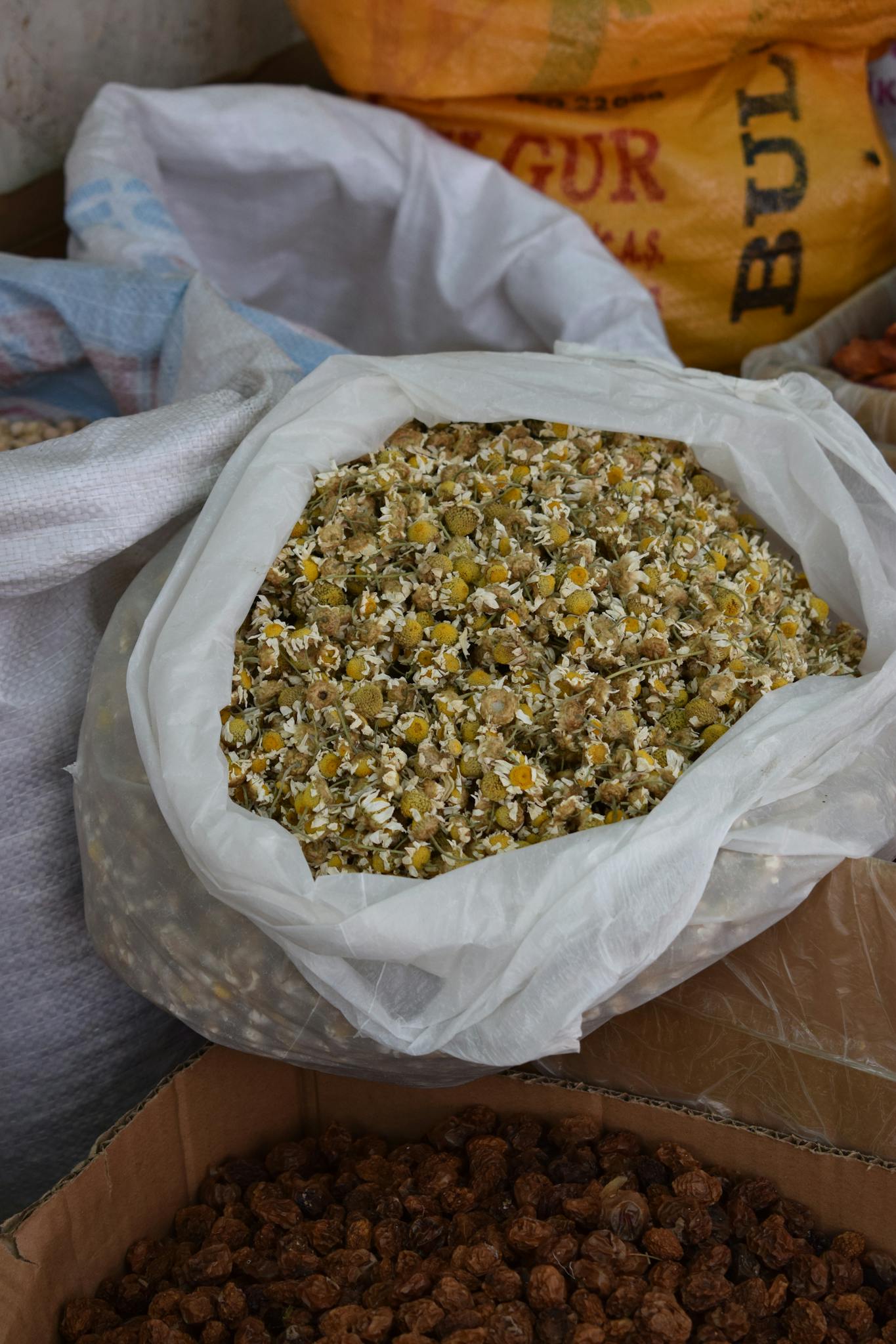Bag of dried chamomile flowers at a local market, perfect for herbal tea use.
