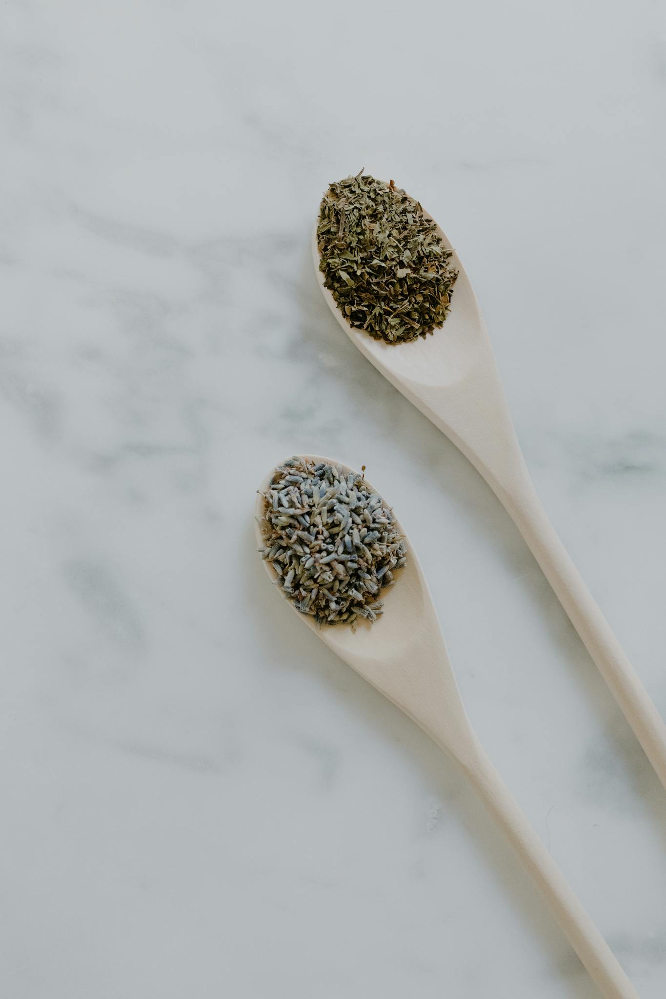 Top view of herbs on wooden spoons for culinary and aromatic use.